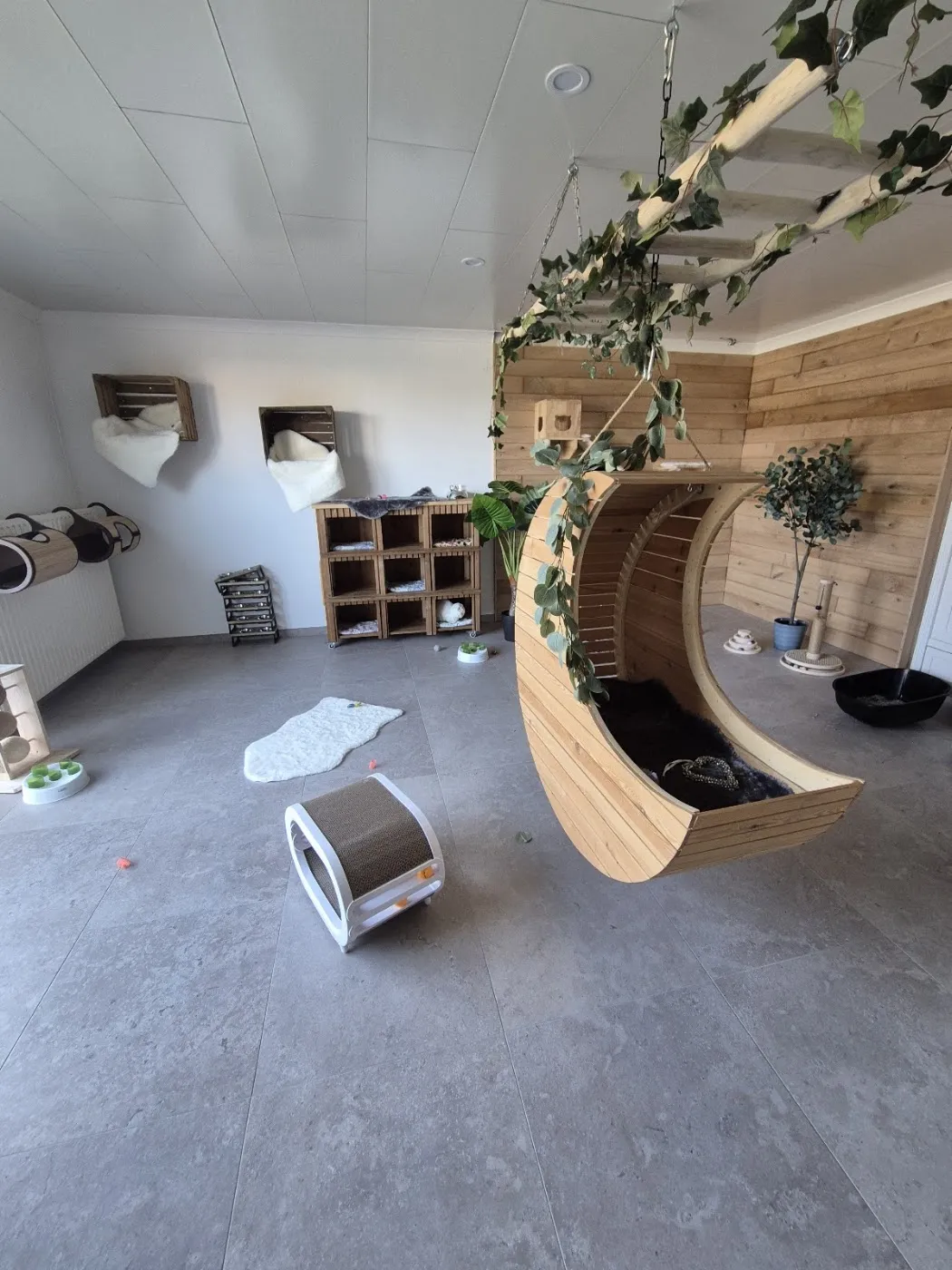 De lichte leefruimte met een houten maan aan het plafond, kistjes aan de muur en slaapkastjes